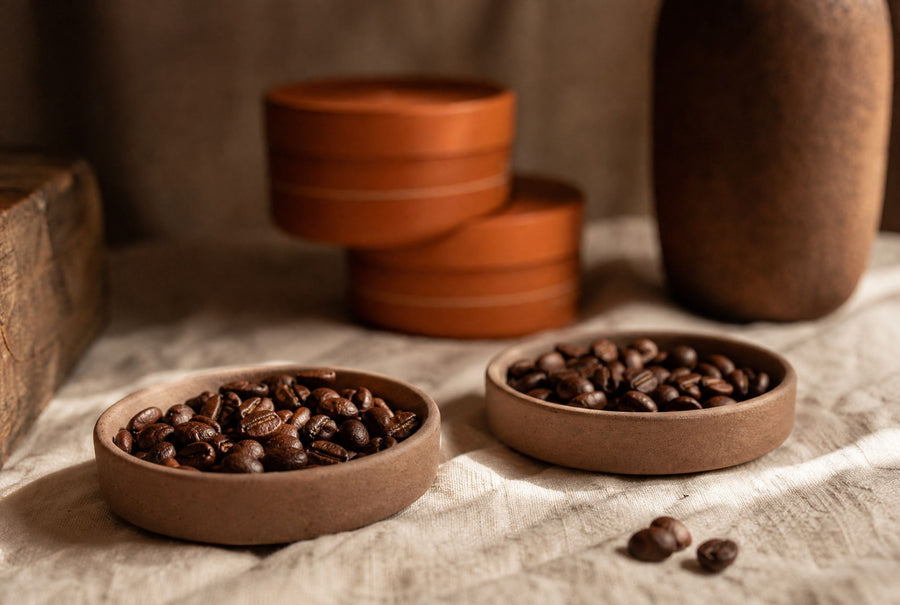 Two dishes of roasted coffee beans side by side on linen, single origin versus blend