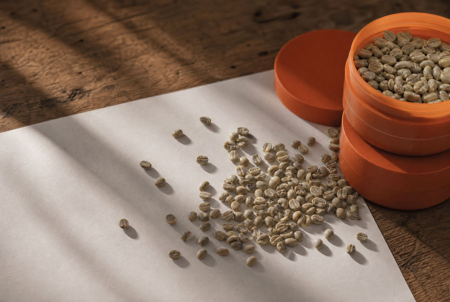 Green coffee beans spilling across a plain paper sheet, mycotoxin screening before roasting