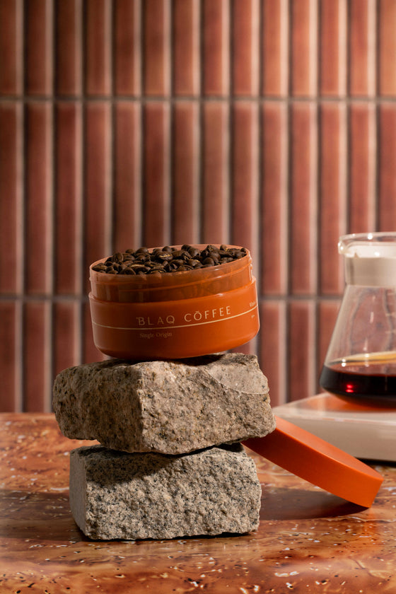 Blaq Coffee Peru Palto. Ceramic container of whole coffee beans on stones.
