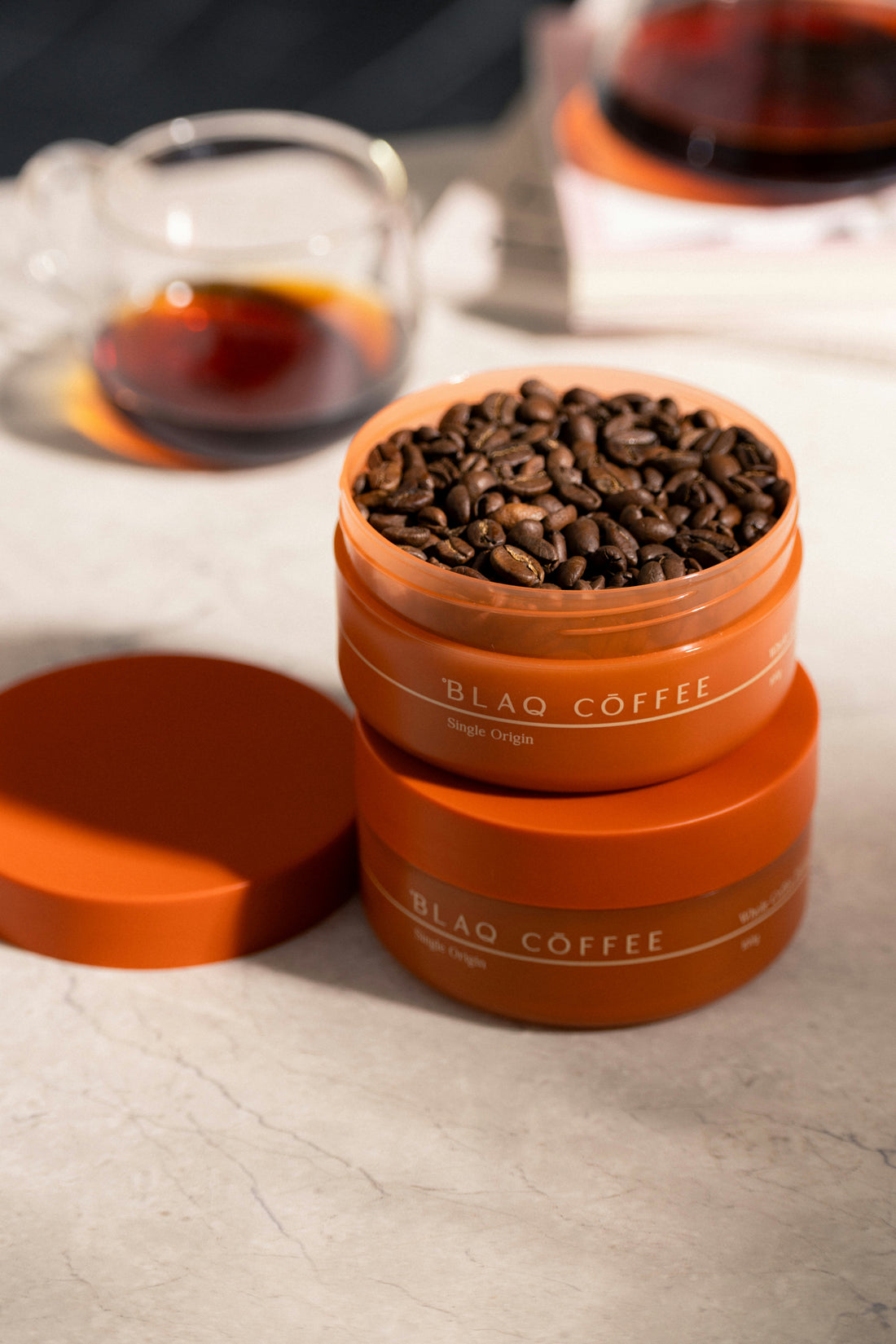 A Blaq Coffee 100g tin in terracotta, photographed in soft window light.