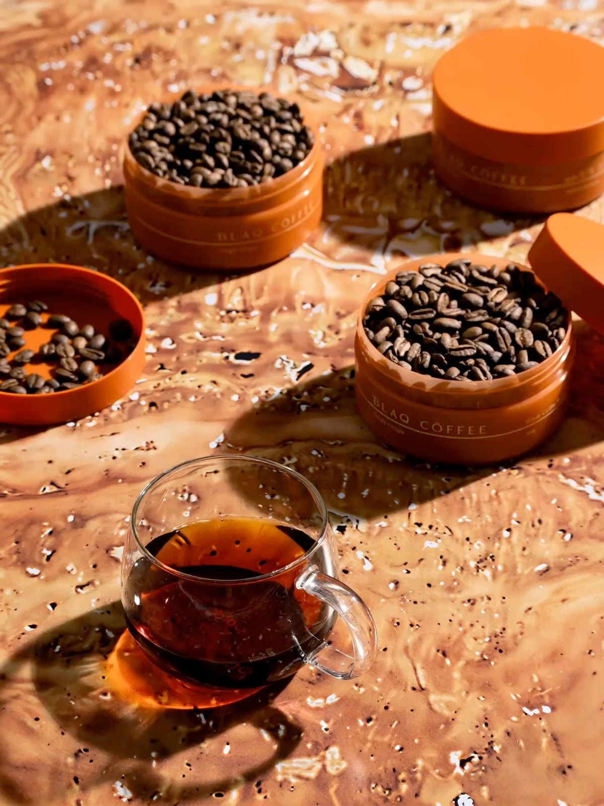 The film's first frame. Blaq Coffee tubs, roasted beans, and a cup of black coffee on burl wood.